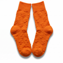 Flat lay of orange Money Socks crew socks standing upright, displaying the embossed 3D dollar-sign pattern down each leg